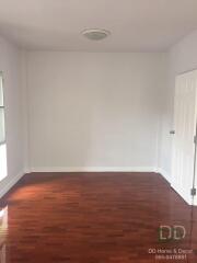 Empty room with hardwood flooring and a door