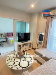 Living room area with television, coffee table, and partial view of a bedroom