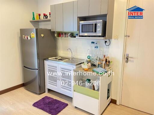 Modern compact kitchen with stainless steel refrigerator, microwave, and sink