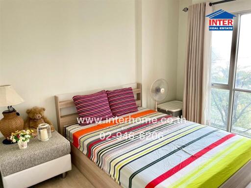 Cozy bedroom with striped bedding, decorative items, and a large window