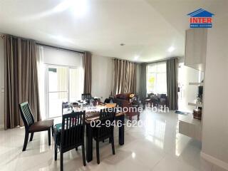 Bright living room with dining table and chairs, large windows, and tiled flooring