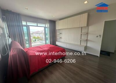 Spacious bedroom with large windows, red bedding, and ample built-in storage