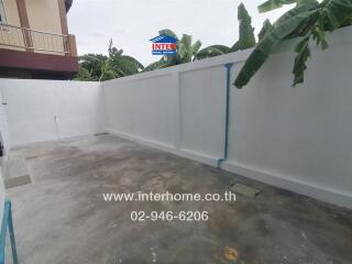 Outdoor concrete area with high white walls and banana trees