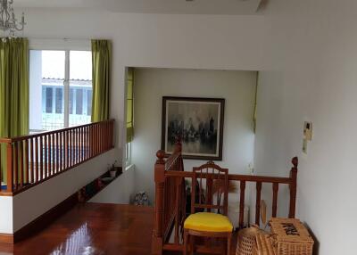 Staircase landing with wooden railings, framed artwork, and green curtains.