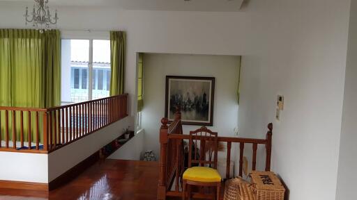 Staircase landing with wooden railings, framed artwork, and green curtains.