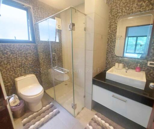 Modern bathroom with glass shower, toilet, and a vanity with a sink.