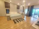 Spacious bedroom with a bed, wooden flooring, and a sliding glass door to the balcony