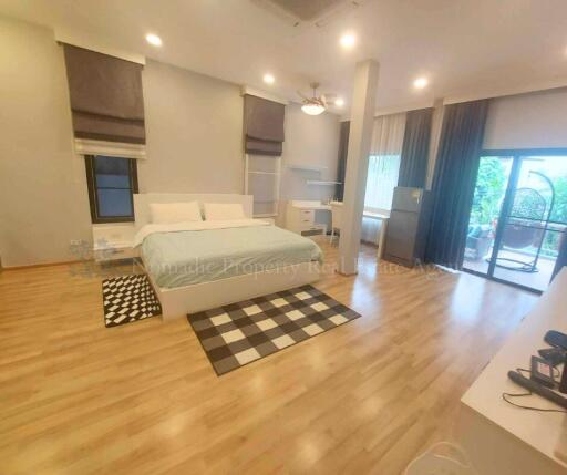 Spacious bedroom with a bed, wooden flooring, and a sliding glass door to the balcony