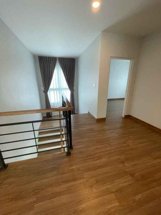 Hallway view leading to bedroom with wood flooring and natural light