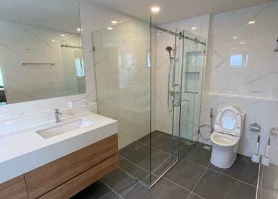 Modern bathroom with glass shower, freestanding sink, and toilet