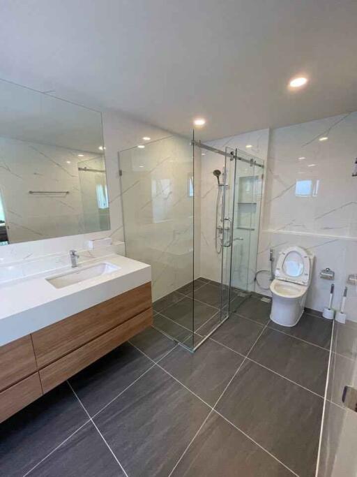 Modern bathroom with glass shower, freestanding sink, and toilet