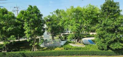 A lushly landscaped outdoor area with trees, a modern art installation, and a partial view of a swimming pool.