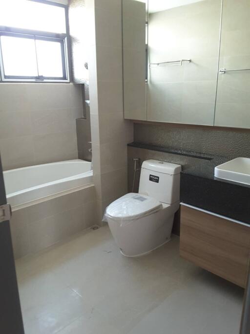 Modern bathroom with bathtub, toilet, sink, and large mirror