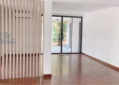 Spacious living room with wooden flooring and glass door leading to a balcony