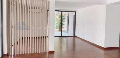 Spacious living room with wooden flooring and glass door leading to a balcony