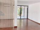 Spacious living room with wooden flooring and glass door leading to a balcony