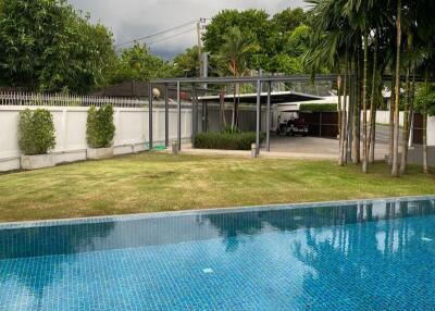 Outdoor pool with a lush garden and a covered parking area