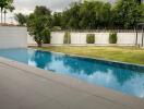 Outdoor pool area with adjacent lawn and fencing