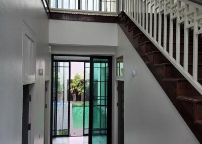 Spacious hallway with staircase and glass doors leading to outdoor area