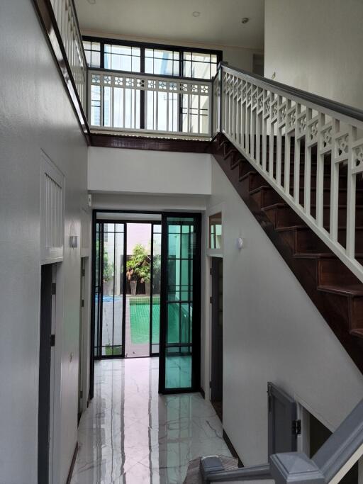 Spacious hallway with staircase and glass doors leading to outdoor area