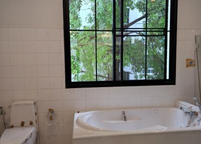 Bathroom with large window, bathtub, and toilet