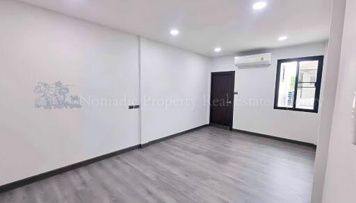 Empty living room with hardwood floor, recessed lighting, and window.