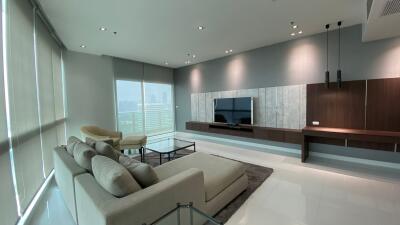 Modern living room with large windows, light grey sofa, TV, and stylish decor