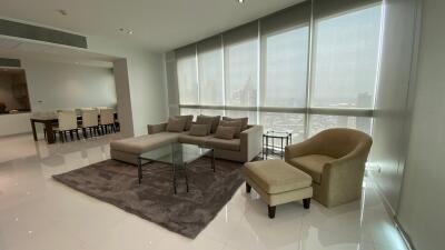 Modern living room with large windows, comfortable seating, and dining area
