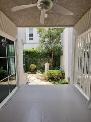 Covered patio with fan and adjacent garden view