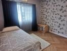 Bedroom with a single bed, patterned wall, wooden floor, and large window with curtains