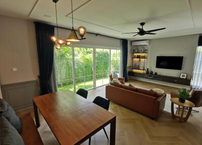 Spacious living room with dining area and large windows overlooking a green garden