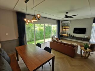 Spacious living room with dining area and large windows overlooking a green garden