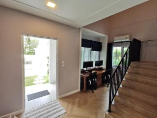 Photo of a multi-purpose living space with an open doorway, desk area, and stairs.