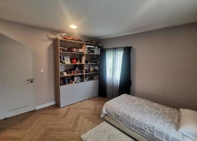Well-lit bedroom with a bookshelf and a single bed.