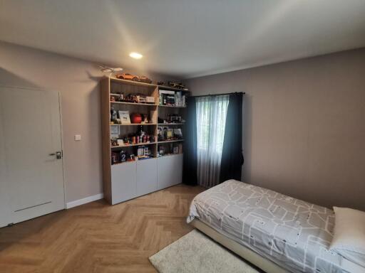 Well-lit bedroom with a bookshelf and a single bed.