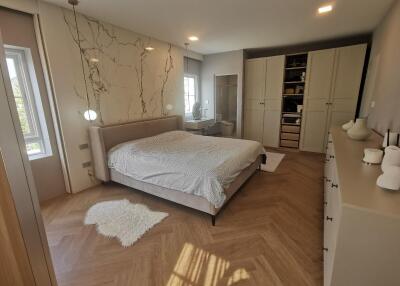 Modern bedroom with wooden floors and accent wall with decorative branches