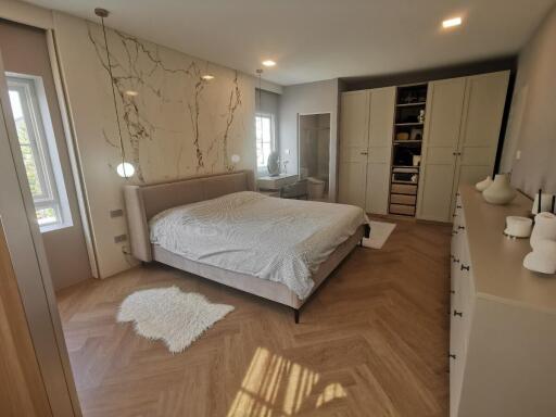 Modern bedroom with wooden floors and accent wall with decorative branches