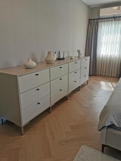 Modern bedroom with large dresser and natural light.