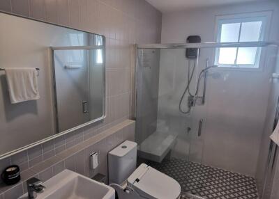 Modern bathroom with tiled walls and floor, glass shower enclosure, and sanitary fixtures