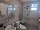 Modern bathroom with tiled walls and floor, glass shower enclosure, and sanitary fixtures