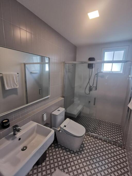 Modern bathroom with tiled walls and floor, glass shower enclosure, and sanitary fixtures