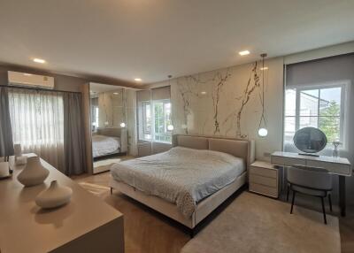 Spacious and modern bedroom with a large bed, mirrored wardrobe, and work desk