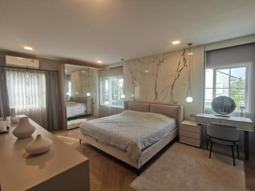 Spacious and modern bedroom with a large bed, mirrored wardrobe, and work desk