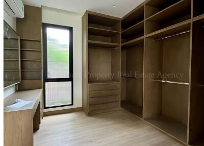 Spacious bedroom with built-in wooden shelving and large window
