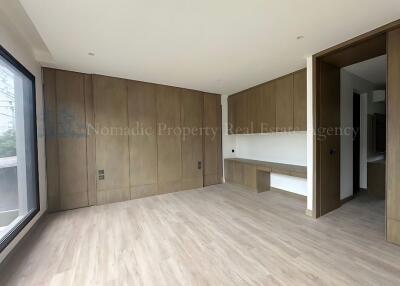 Spacious modern bedroom with wooden flooring and built-in storage