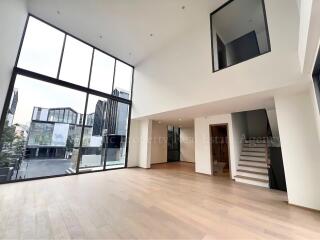 Spacious open-plan living area with large windows and modern staircase