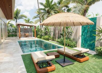 Outdoor pool area with lounge chairs, umbrella, and tropical landscaping