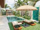 Outdoor pool area with lounge chairs, umbrella, and tropical landscaping