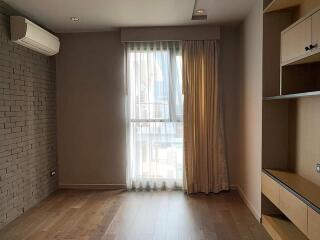 Bedroom with air conditioning, large window, wooden flooring, brick accent wall, and built-in shelves