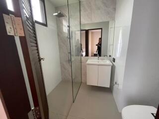 Modern bathroom with glass shower, sink, and toilet